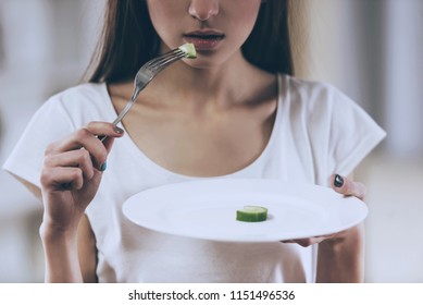 Young Thin Girl Eat Cucumber. Closeup Portrait. Essence Of Malnutrition. Diets. Anorexia Concept. Isolated Background. Skinny Waist. Abnormal Weight Loss. Unhealthy Nutrition. Anorexic Girl.