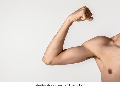 Young thin man arm on a grey background. Weak man muscle flexing. Skinny man goes in for sports, builds muscles. Male shows small biceps. Man is preparing for training. Sport and health concept. - Powered by Shutterstock