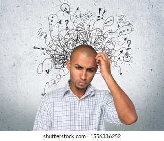 A young thinking man scratches his head with an illustration of confused thoughts - Shutterstock ID 1556336252