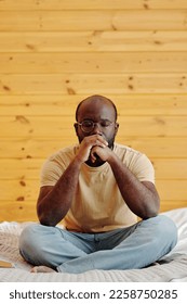 Young thoughtful African American man sitting on bed and expressing deep concentration on his thoughts to solve some problem - Shutterstock ID 2258750285