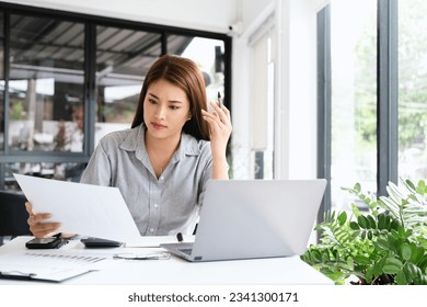Young thoughtful Asian business woman executive manager wearing shirt working in modern office, taking notes and thinking of professional plan, project management, considering new business ideas. - Shutterstock ID 2341300171