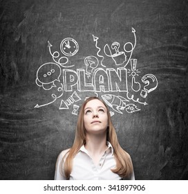 A Young Thoughtful Business Lady Is Dreaming About Building Of A Business Plan For Business Development. Business Plan Sketch Is Drawn On The Black Chalkboard.