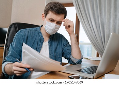 Young Thoughtful Man In Protective Face Mask Studying And Working Remotely Due To Coronavirus Or COVID-19 Quarantine. Online Training Education And Freelance Work With Laptop From Home. Lost Job