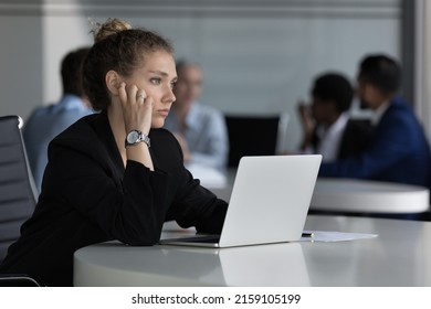 Young thoughtful woman sit at desk with laptop looks into distance feels unmotivated or unsure working on on-line task, experiences problem with solution. Challenge, corporate office workflow concept