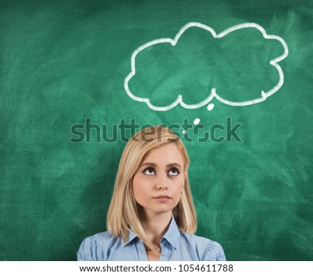 Young thoughtful woman standing on green blackboard