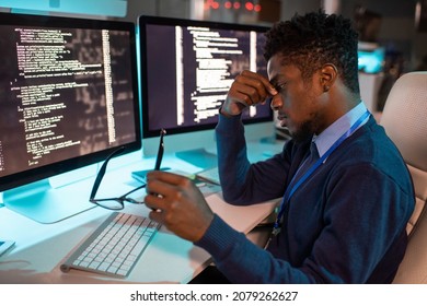 Young Tired African Businessman Sitting By Workplace Late At Night While Trying To Concentrate And Continue Working