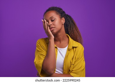 Young tired beautiful African American woman exhausted closes eyes touches face with palm wants to sleep after hard day at work or long walk with friends stands on lilac purple background - Powered by Shutterstock