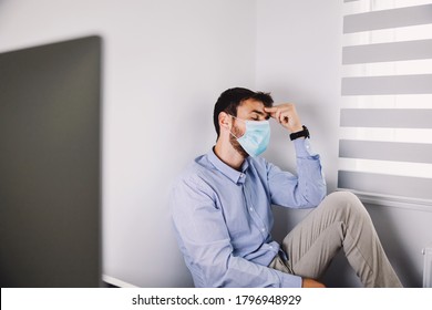 Young tired businessman with face mask on sitting in his office and taking a break during corona virus outbreak. - Powered by Shutterstock