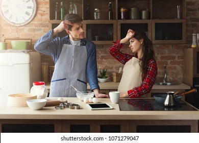 Young Tired Couple Baking Pie And Having Problems In Loft Kitchen. Young Family Cooking At Home, Using Digital Tablet. Mockup For Recipe