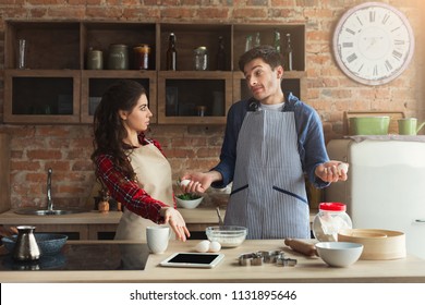 Young Tired Couple Baking Pie And Having Problems In Loft Kitchen. Young Family Cooking At Home, Using Digital Tablet. Mockup For Recipe