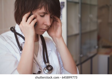 A Young Tired Doctor Talks On The Phone After A Difficult Day.