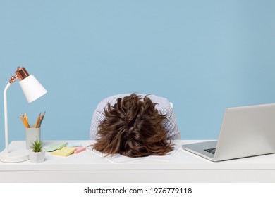 Young tired exhausted frustrated secretary employee business woman wearing casual shirt sit work sleep laid her head down on white office desk with pc laptop isolated on pastel blue background studio