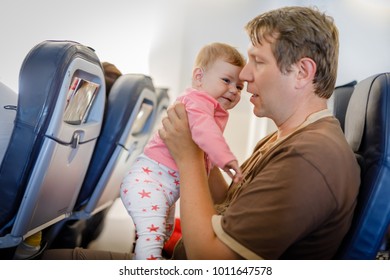 Young Tired Father And His Crying Baby Daughter During Flight On Airplane Going On Vacations