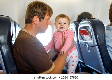 Young Tired Father And His Crying Baby Daughter During Flight On Airplane Going On Vacations