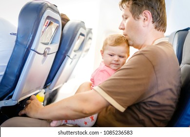 Young Tired Father And His Crying Baby Daughter During Flight On Airplane Going On Vacations