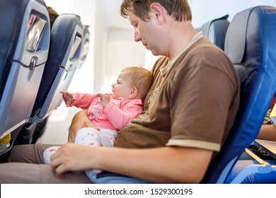 Young Tired Father And His Crying Baby Daughter During Flight On Airplane Going On Vacations