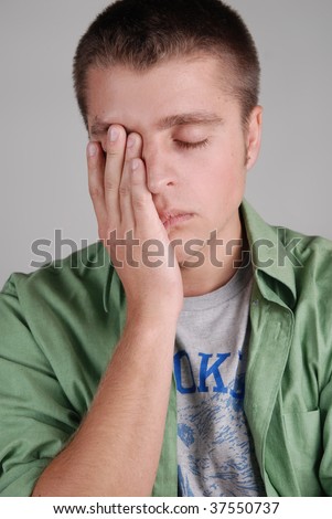 Young tired man, clothing his face with his hand