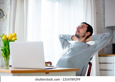 Young tired man sitting at table with claptop computer. Kitchen location. - Shutterstock ID 1314789299