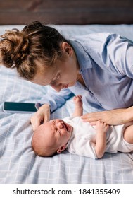 Young Tired Mother Soothing A Crying Baby. The Newborn Is Crying Worried About A Sore Tummy. Infant Colic. Motherhood 