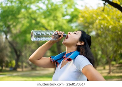 Young Tired Thirsty Indian Woman Athlete Takes A Break Drinking Water With Bottle, Asian Female Out On A Run On A Hot Day In The Park.