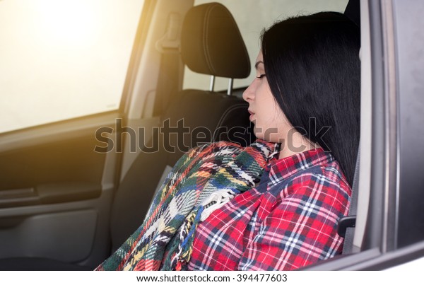 Young tired woman driver sleeping on the driver seat\
in the car