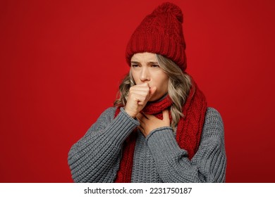 Young tired woman wears gray sweater scarf hat cover mouth with hands sneezy cough isolated on plain red background studio portrait. Healthy lifestyle ill sick disease treatment cold season concept - Shutterstock ID 2231750187