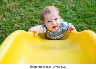 Young Toddler Boy Child Playing On Slide At Playground Outdoors During Summer