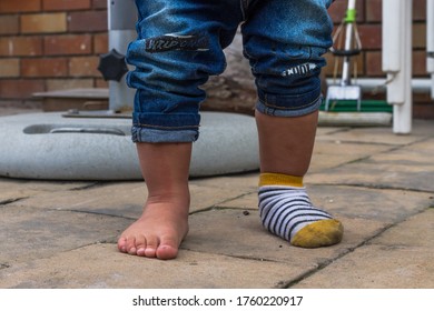 Young Toddler Feet With One Sock On, Funny Baby Feet One Sock. Cute Baby Feet.