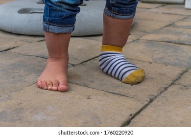 Young Toddler Feet With One Sock On, Funny Baby Feet One Sock. Cute Baby Feet.