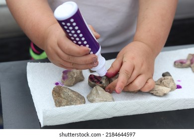 Young Toddler Two Year Old Girl Developing Her Fine Motor Skills Through Play By Using A Dot Marker To Paint Rocks