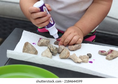 Young Toddler Two Year Old Girl Developing Her Fine Motor Skills Through Play By Using A Dot Marker To Paint Rocks