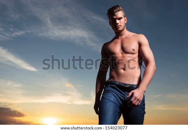 Young Topless Man Outdoor Looking Down At The Camera With The Sunset Behind