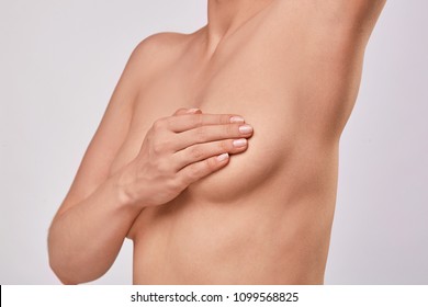 Young topless woman doing breast self-exam (BSE). Checking up breast changes, possible lumps, distortions or swelling.  Breast cancer awareness. 