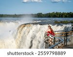 Young tourist admiring the imposing Iguazú Falls, Argentina. Young woman enjoying her vacation at Iguazu Falls, Argentina. Beautiful view of the Devil