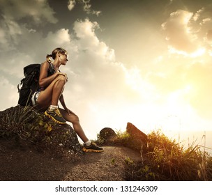 Young tourist with backpack relaxing on rock and enjoying sunset