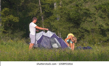 Young tourist couple setting up a tent together during an active summer vacation in the peaceful countryside. Sporty man and his girlfriend working together to pitch a tent by the tranquil forest. - Powered by Shutterstock