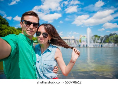 Young Tourist Couple Traveling On Holidays In Europe Smiling Happy. Caucasian Girl And Man Making Selfie Background Of Fountain