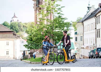 Young Tourist Couple Travellers With Electric Scooters In Small Town, Talking.