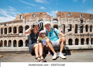 Young Tourist Family Sitting In Front Of Colosseum In Rome, Italy