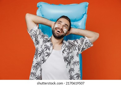 Young Tourist Man With Spf Sunscreen Cream On Wear Beach Shirt Lies On Blue Inflatable Mattress Hotel Pool Look Overhead Isolated On Plain Orange Background. Summer Vacation Sea Rest Sun Tan Concept