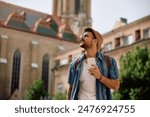 Young tourist using cell phone while standing on town square. Copy space. 