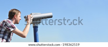 Young tourist watching through binoculars or telescope 