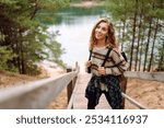 Young tourist woman enjoys the view of the mountain lake. Solitude with nature. Active lifestyle.