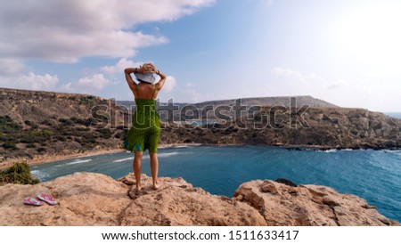 Young tourist woman looking at Ghajn Tuffieha bay. Panoramic view, Malta island.