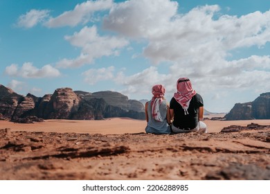 Young tourists enjoying the scenery over Wadi Rum desert with high mountains and red sand, couple on a honeymoon in Jordan