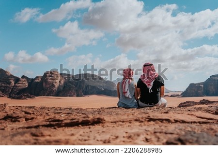 Young tourists enjoying the scenery over Wadi Rum desert with high mountains and red sand, couple on a honeymoon in Jordan