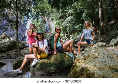 Young tourists are resting on the rocks in the jungle waterfall in the background - Shutterstock ID 394883836