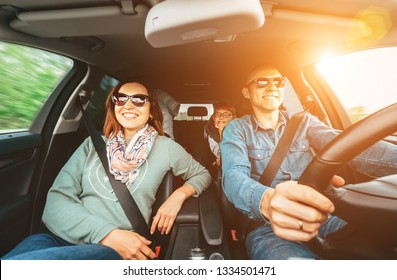 Young Traditional Family Has A Long Auto Journey And Cheerfully Singing Aloud The Favorite Song Together. Safety Riding Car Concept Wide Angle Inside Car View Image.