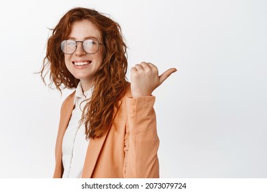 Young Trainee Pointing Finger Right, Showing Advertisement And Smiling. Businesswoman Demonstrating Graph Or Chart Aside, Showing Logo, Standing In Suit Over White Background