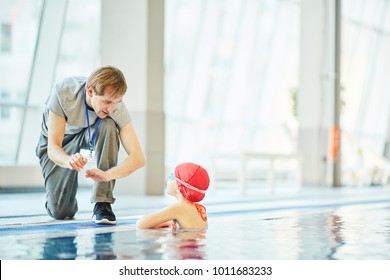 Young trainer explaining little swimmer what to do in extreme situation in water - Powered by Shutterstock